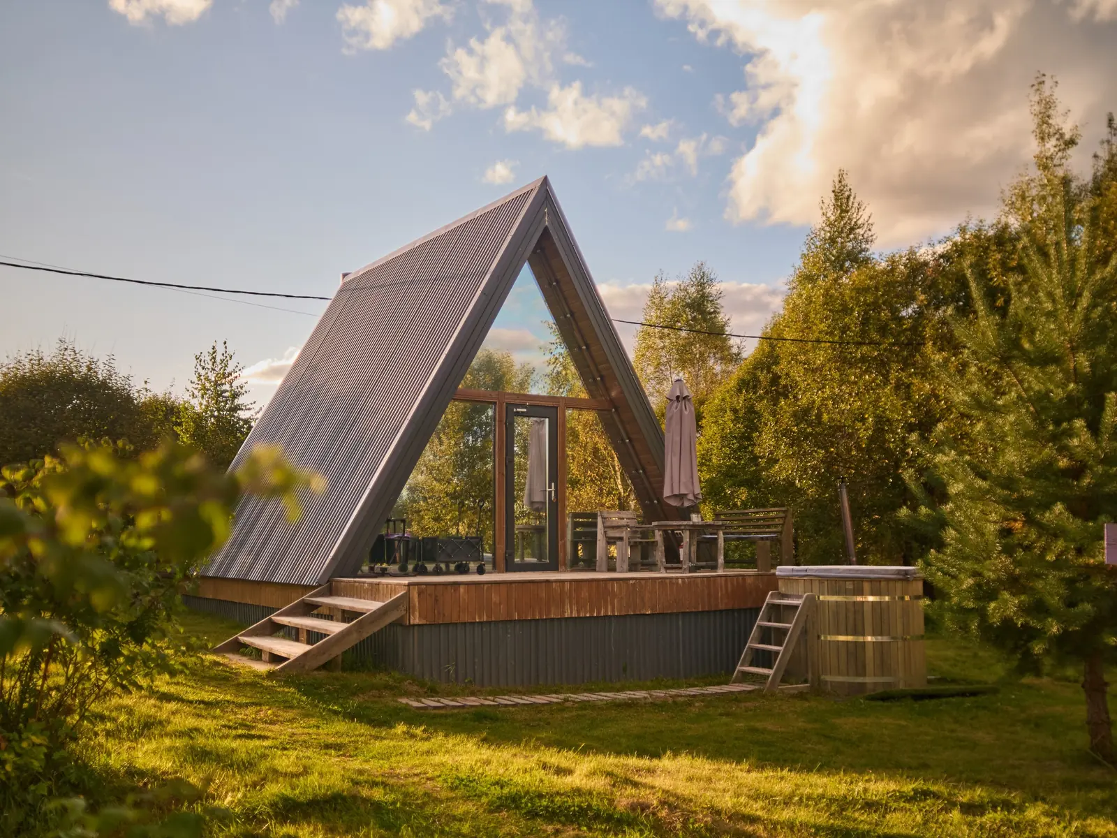 A-frame «Малина» фито-отеля «Лаванда» в вечернем солнце: терраса и деревянная купель среди сосен