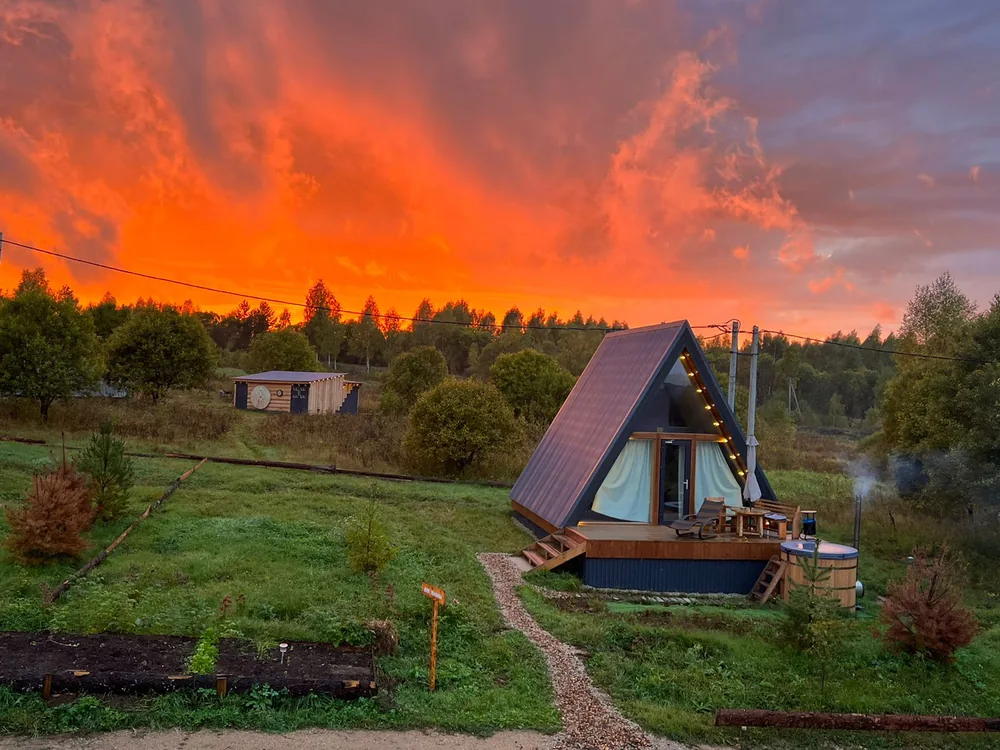A-frame домик фито-отеля «Лаванда» с кедровой купелью на террасе, оранжевое небо на закате